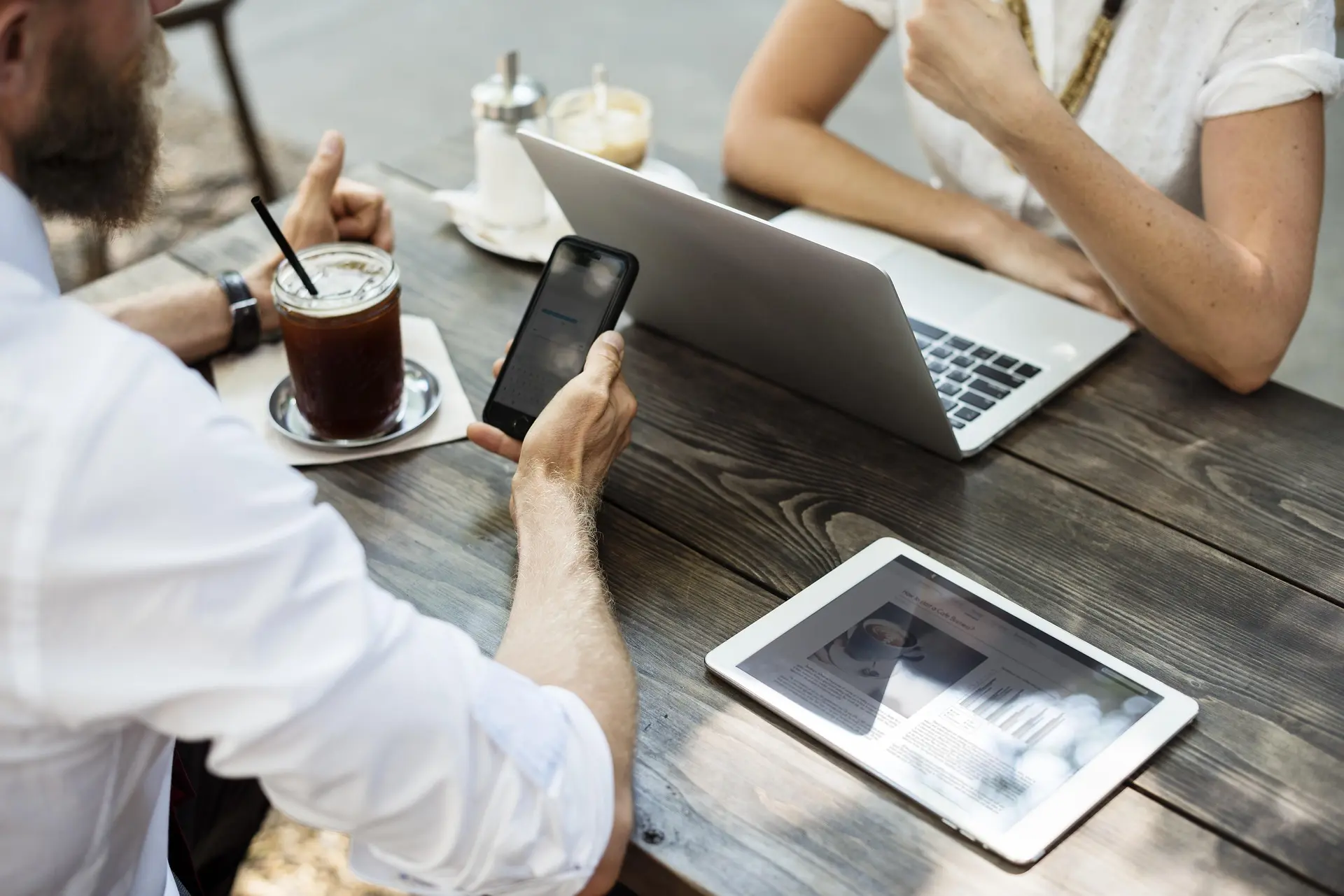 Business owners juggling a laptop, phone and tablet to manage work